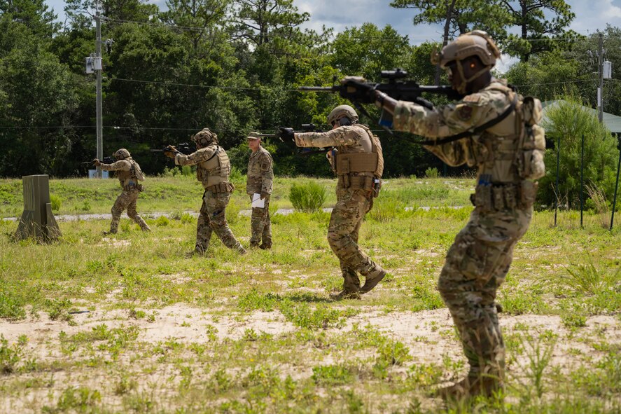 Team of Airmen holding weapons walk slowly forward.