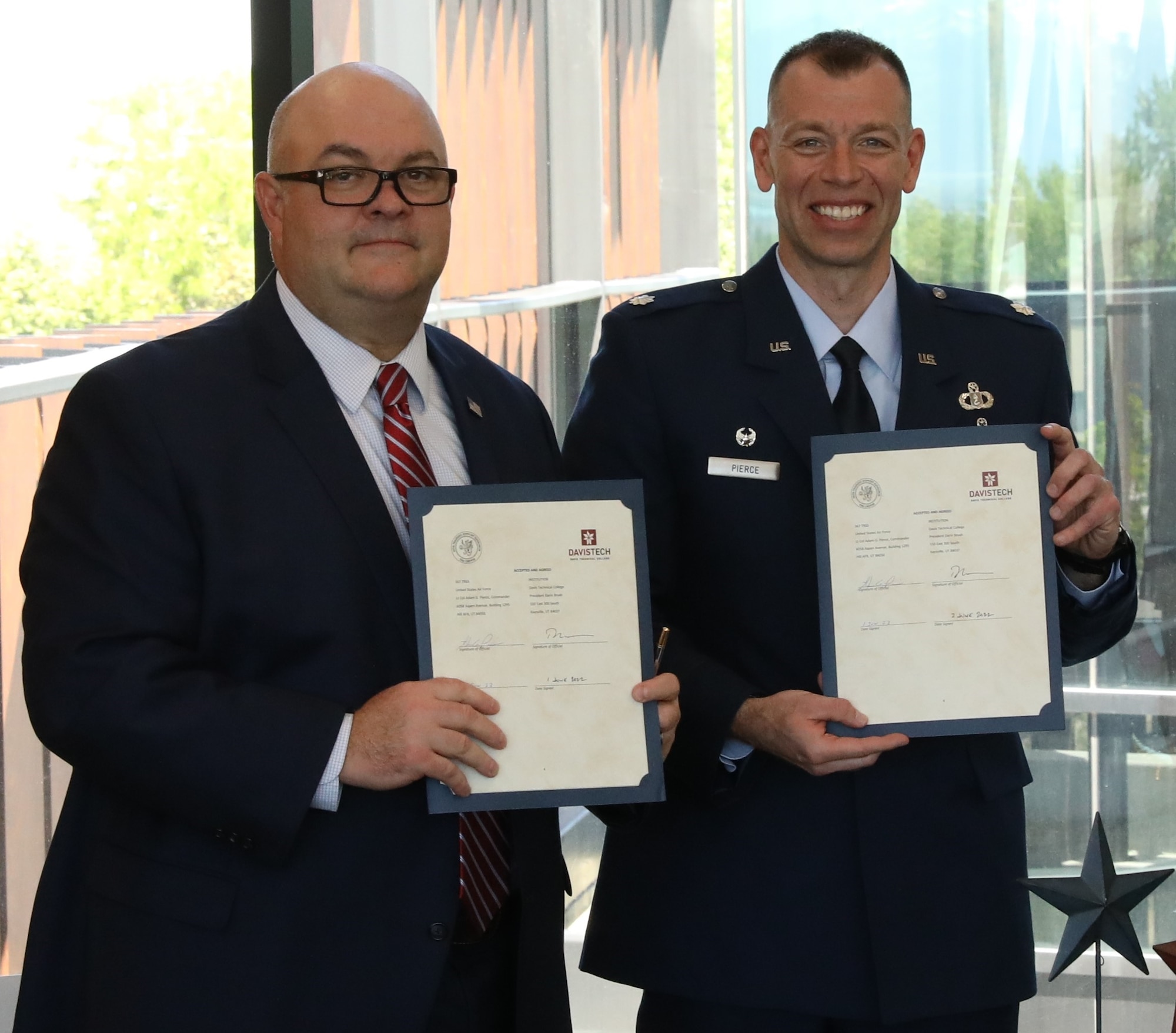 Davis Technical College president Darrin Brush and Lt. Col. Adam Pierce, 367th Training Support Squadron commander display the educational and professional develop partnership agreement that customizes formal training for 367th TRSS members