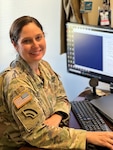 Chief Warrant Officer 3 Katie Harrell poses in uniform at a computer