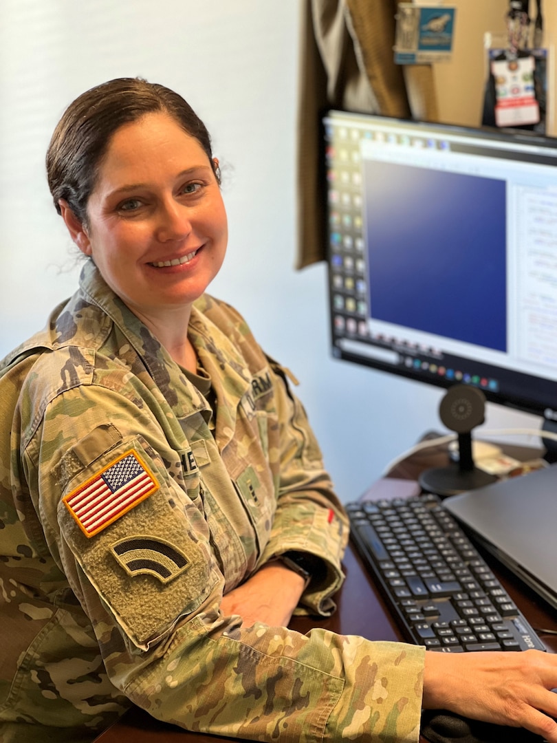 Chief Warrant Officer 3 Katie Harrell poses in uniform at a computer