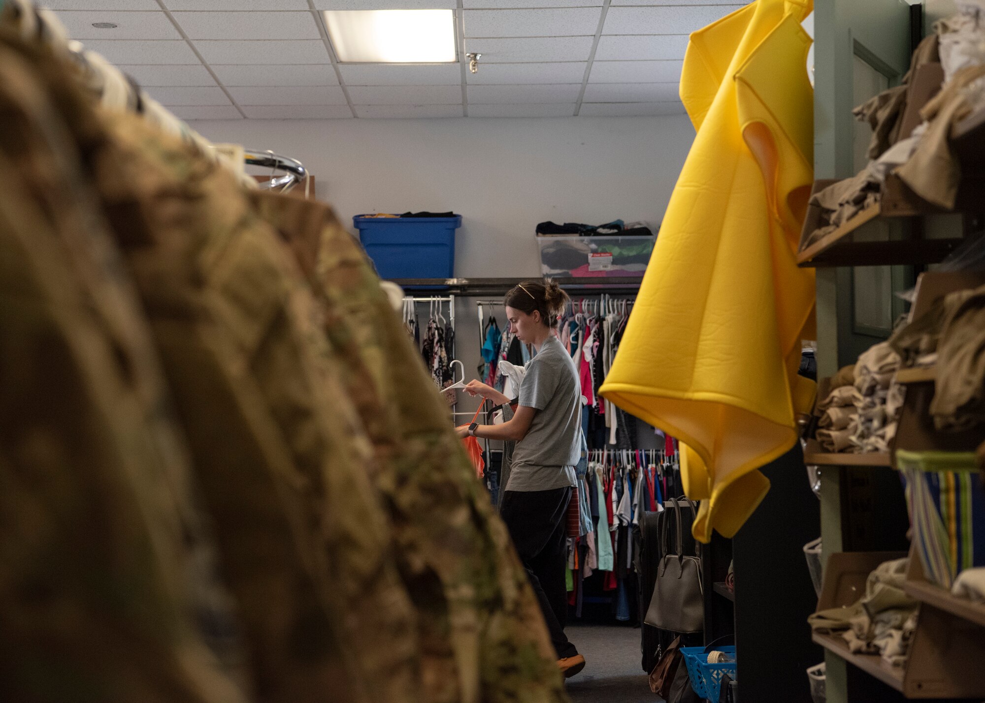 A woman looks through a clothing rack holding civilian clothing.
