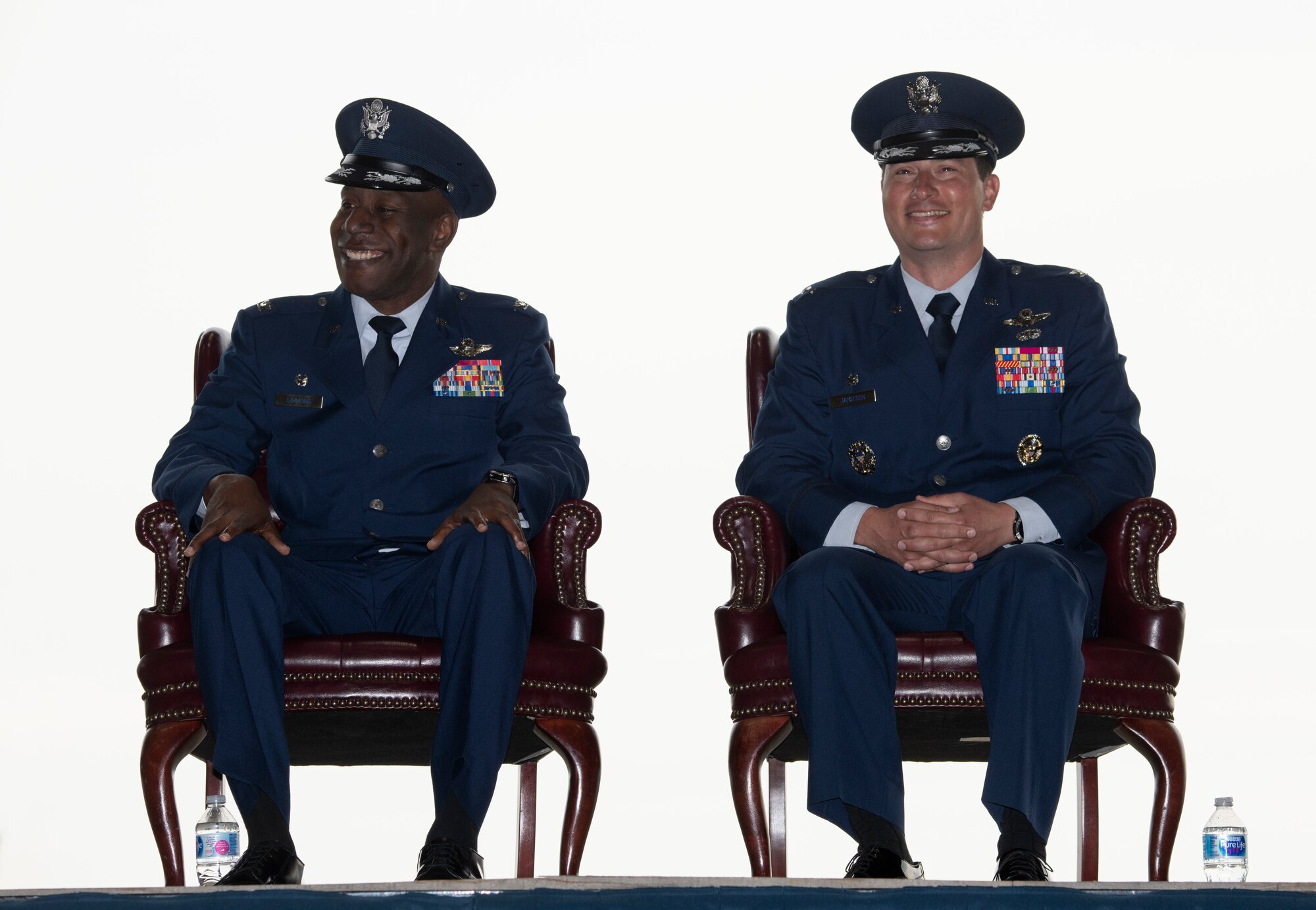 U.S. Air Force Col. Travolis A. Simmons and Col. Kevin M. Jamieson share a moment of levity while sitting on stage