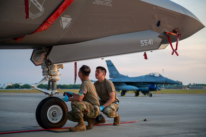 Photo of Airmen kneeling by an aircraft tire.