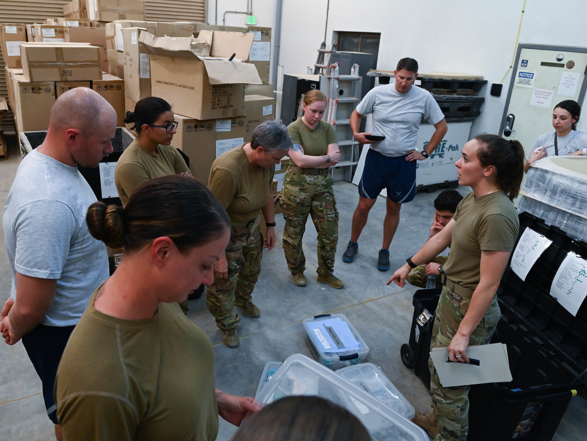 U.S. Air Force Staff Sgt. Mary Hicks (right), a 379th Expeditionary Air Evacuation Squadron biological environmental technician, briefs other members of the 379th EAES during an exercise July 11, 2022 at Al Udeid Airbase, Qatar. The medical evacuation staff drilled in the practice of utilizing a negative pressurized container for transporting highly contagious patients to medical facilities. (U.S. Air National Guard photo by Tech. Sgt. Michael J. Kelly)