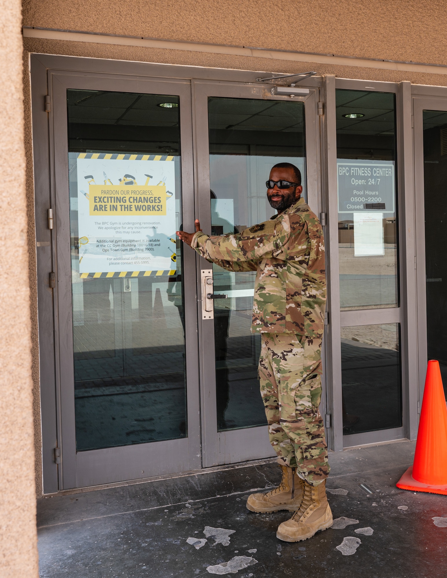 U.S Air Force Master Sgt. Matthew Davis, 379th Expeditionary Force Support Squadron sports and fitness section chief, stands beside the Blatchford-Preston Complex Gym door on Al Udeid Air Base, Qatar, 16 July 2022, showcasing the sign that says "Exciting changes are in the works". Davis helped make many of the important decisions on what kind of materials and equipment was selected for the gym renovation project, set to conclude April 2023. (U.S Air Force photo by Staff Sgt. Dana Tourtellotte)