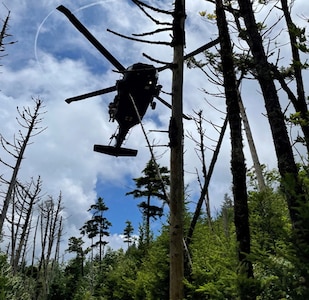 A Tennessee Army National Guard UH-60 Black Hawk helicopter aircrew prepares to hoist a hiker with a life-threatening illness and a Tennessee National Guard flight paramedic into the helicopter on Mount LeConte at the Great Smoky Mountains National Park area July 19.