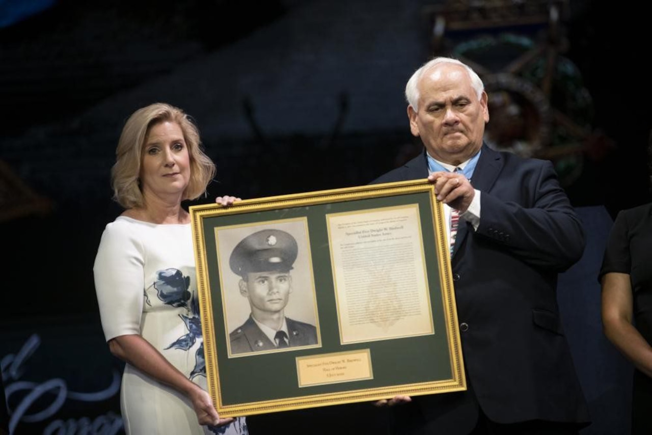 A man and a woman hold a large plaque.