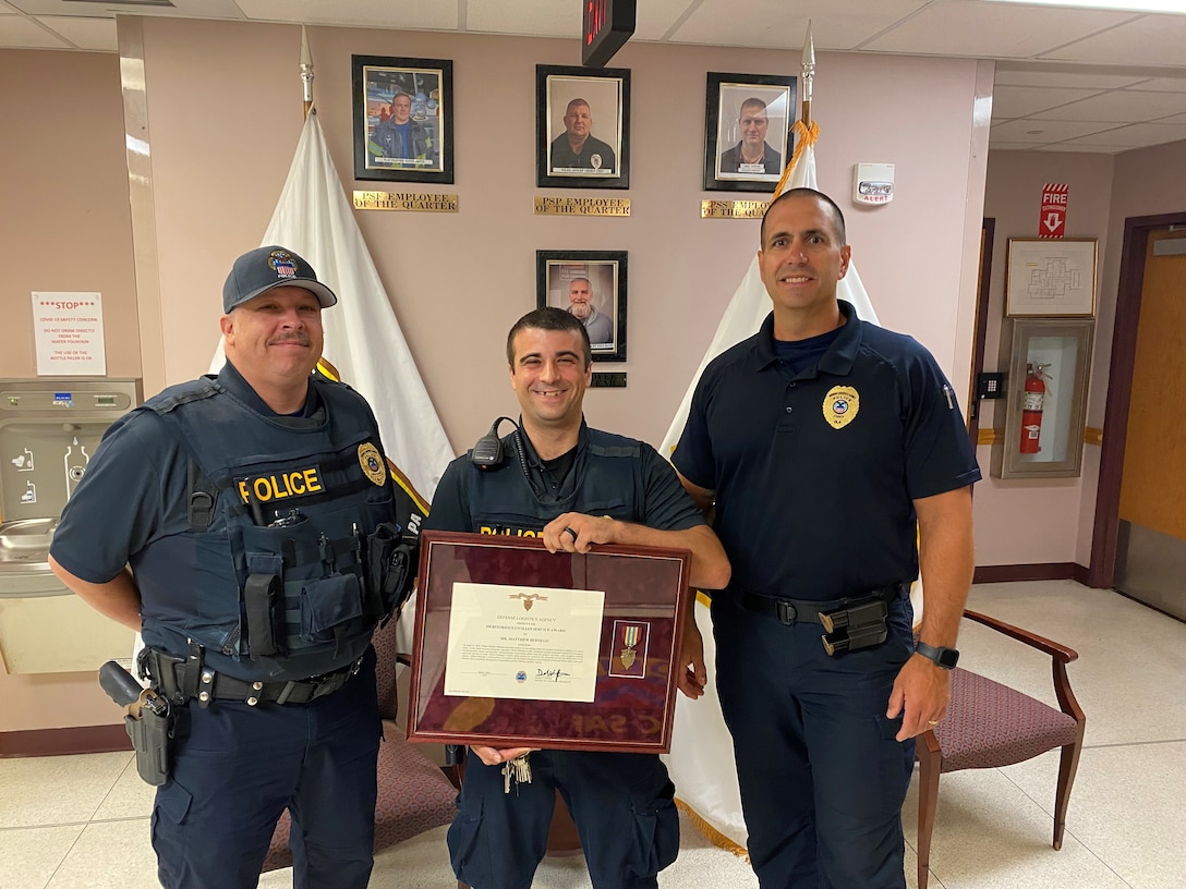 Three DLA Police Officers, the middle one receiving an award.