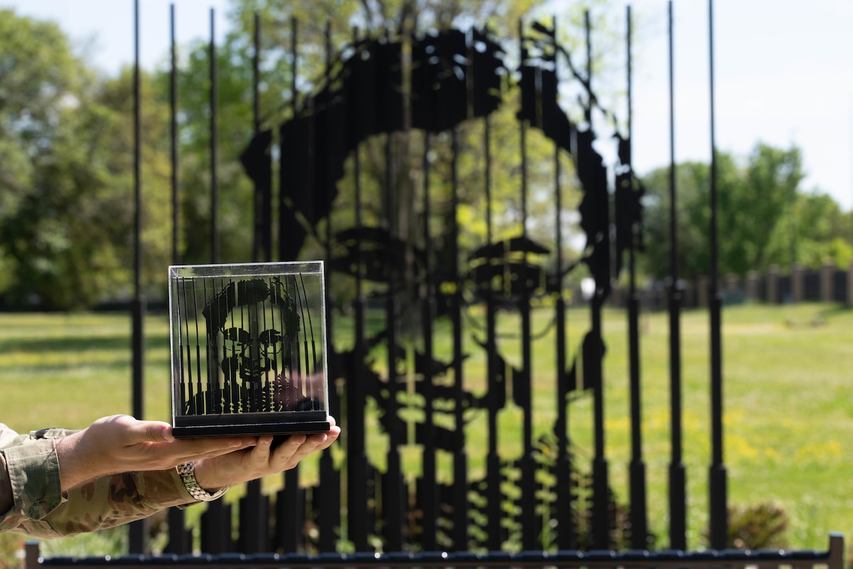 An Air University Airman poses for a photo with a replica of the Rosa Parks memorial on Maxwell Air Force Base