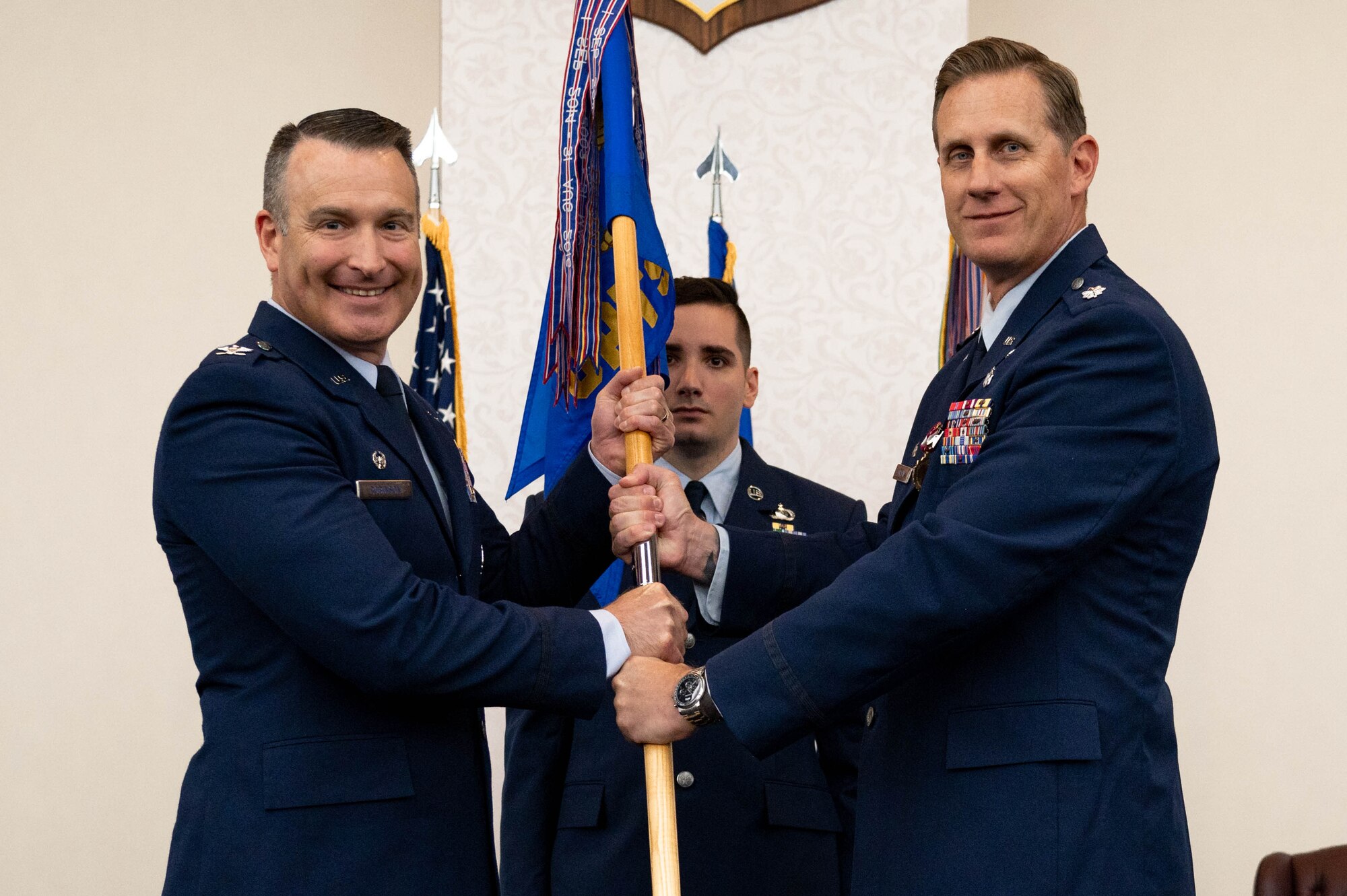 Two airmen hold flag on stage