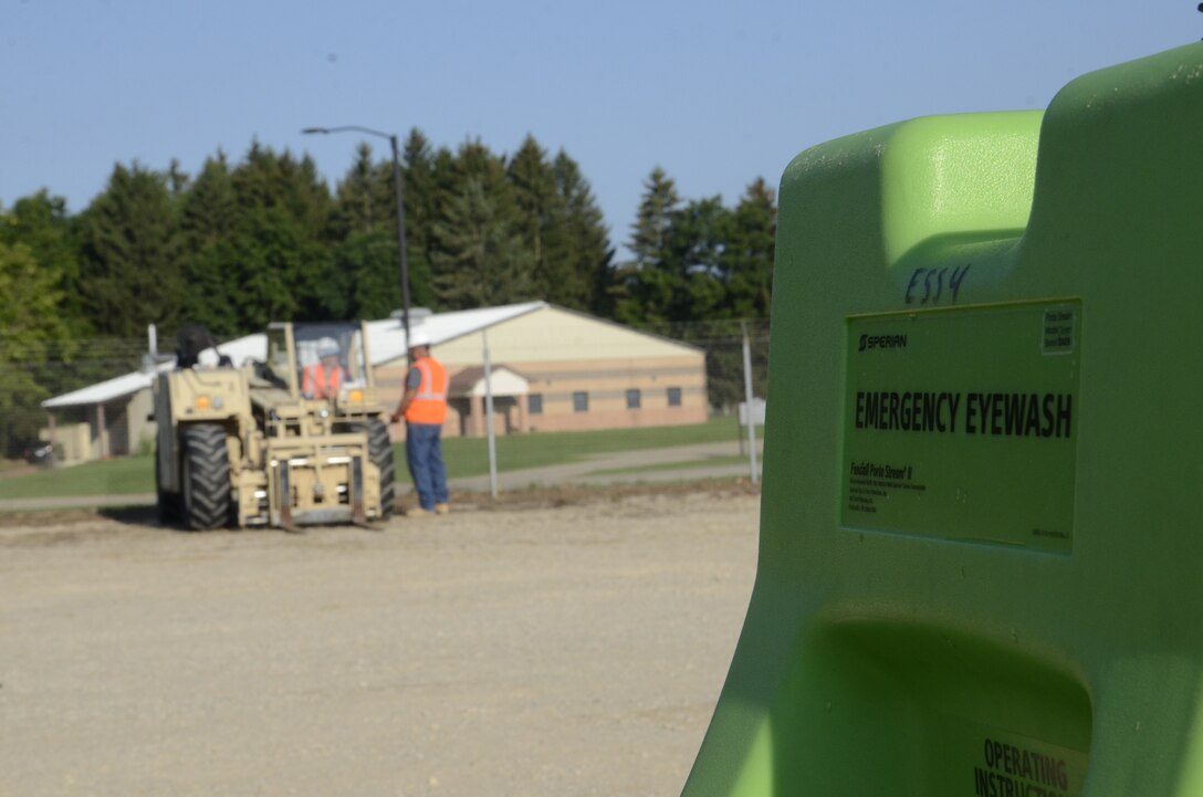 men work in background of eye wash station