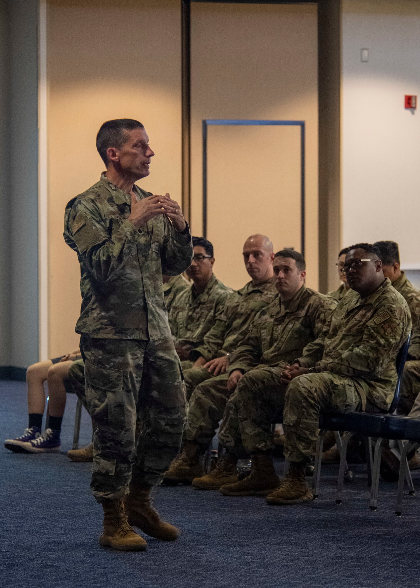 A general paces in front of a seated crowd.