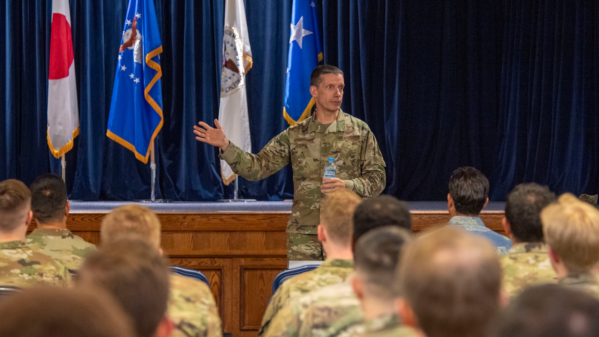 A general gestures to a seated crowd