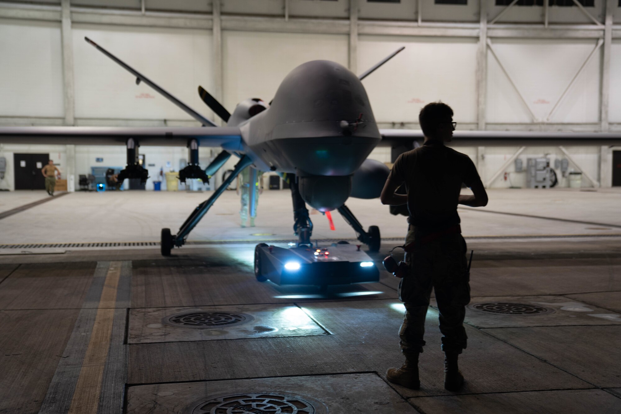 MARINE CORPS BASE HAWAII, Hawaii (July 13, 2022) - A U.S. Air Force maintainer, assigned to the 29th Air Maintenance Unit, tows the MQ-9A Reaper through the hangar at Marine Corps Air Station Kaneohe Bay during Rim of the Pacific (RIMPAC) 2022, July 13. Unmanned and remotely operated vessels extend the capability of interconnected manned platform sensors to enhance the warfighting capacity of multinational joint task forces. Twenty-six nations, 38 ships, four submarines, more than 170 aircraft and 25,000 personnel are participating in RIMPAC from June 29 to Aug. 4 in and around the Hawaiian Islands and Southern California. The world's largest international maritime exercise, RIMPAC provides a unique training opportunity while fostering and sustaining cooperative relationships among participants critical to ensuring the safety of sea lanes and security on the world's oceans. RIMPAC 2022 is the 28th exercise in the series that began in 1971. (U.S. Air Force photo by Airman 1st Class Ariel O'Shea)