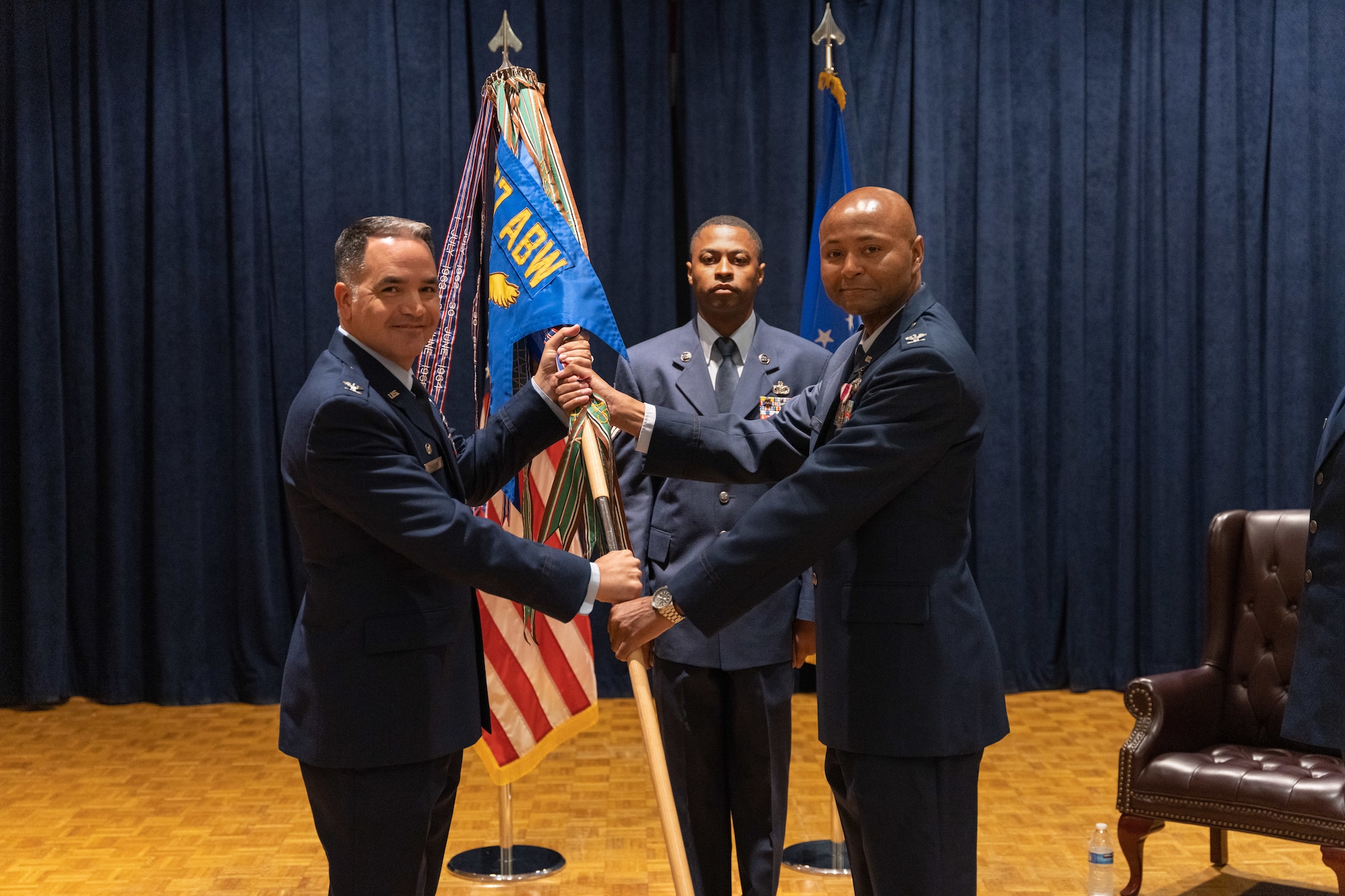 Two commanders pose for a photo with a guidon.