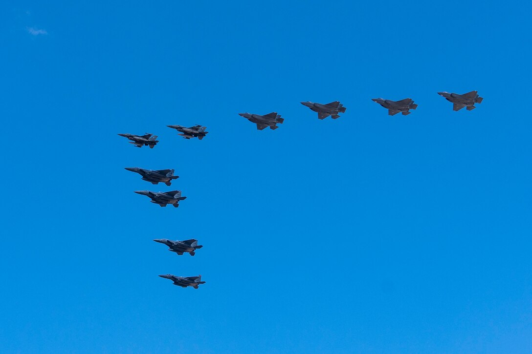 Fighter jets fly in a V formation in a clear blue sky.