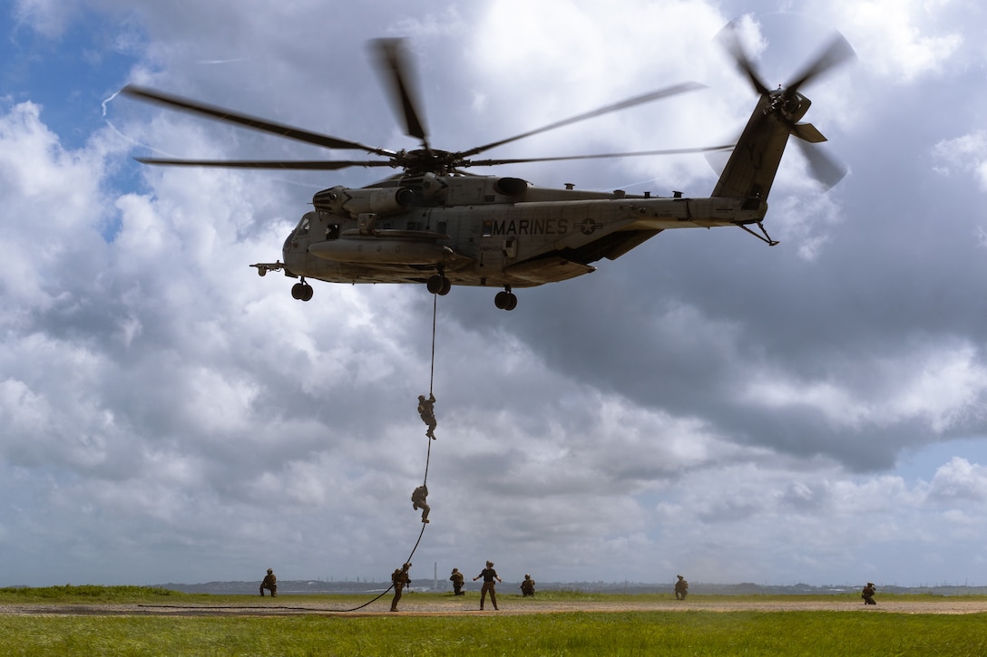 Marines use a rope to descend from a helicopter.