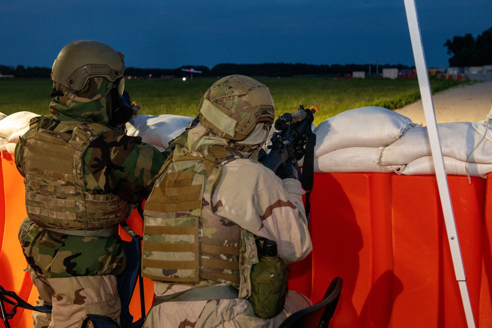 Members from the 512th and 436th security forces squadrons guard an entry control point during the Liberty Eagle Readiness Exercise at Dover Air Force Base, Delaware, July 14, 2022. Both squadrons demonstrated their ability to guard ECPs while wearing mission oriented protective posture gear at the simulated forward operating base, located on Dover AFB, July 11-15, 2022. The purpose of this exercise was to validate both wings' ability to generate, employ and sustain airpower across the world in a contested and degraded operational environment. (U.S. Air Force photo by Senior Airman Ruben Rios)