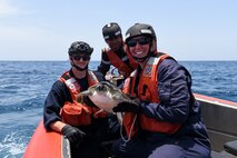(Left to right) U.S. Coast Guard Petty Officer 3rd Class Dylan Neathery, Senegalese Navy Lt. Papa Ousmane Sylla, and U.S. Coast Guard Petty Officer 2nd Class Caitlyn Mason pose for a photo after rescuing a sea turtle caught in a fishing net in the Atlantic Ocean, July 14, 2022. USCGC Mohawk is on a scheduled deployment in the U.S. Naval Forces Africa area of operations, employed by U.S. Sixth Fleet to defend U.S., allied, and partner interests. (U.S. Coast Guard photo by Petty Officer 3rd Class Jessica Fontenette)
