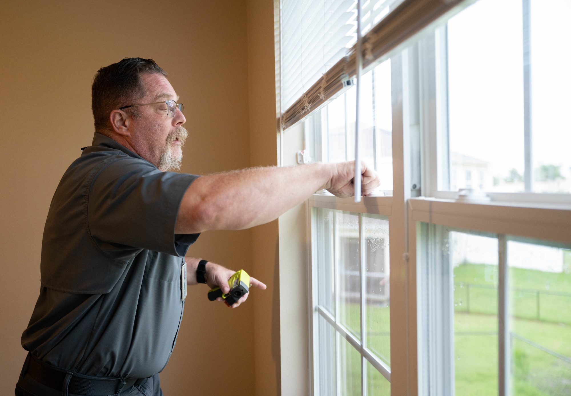 A man checks the window seal of a home