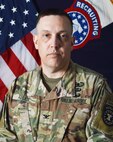 Man wearing Army uniform standing in front of flag