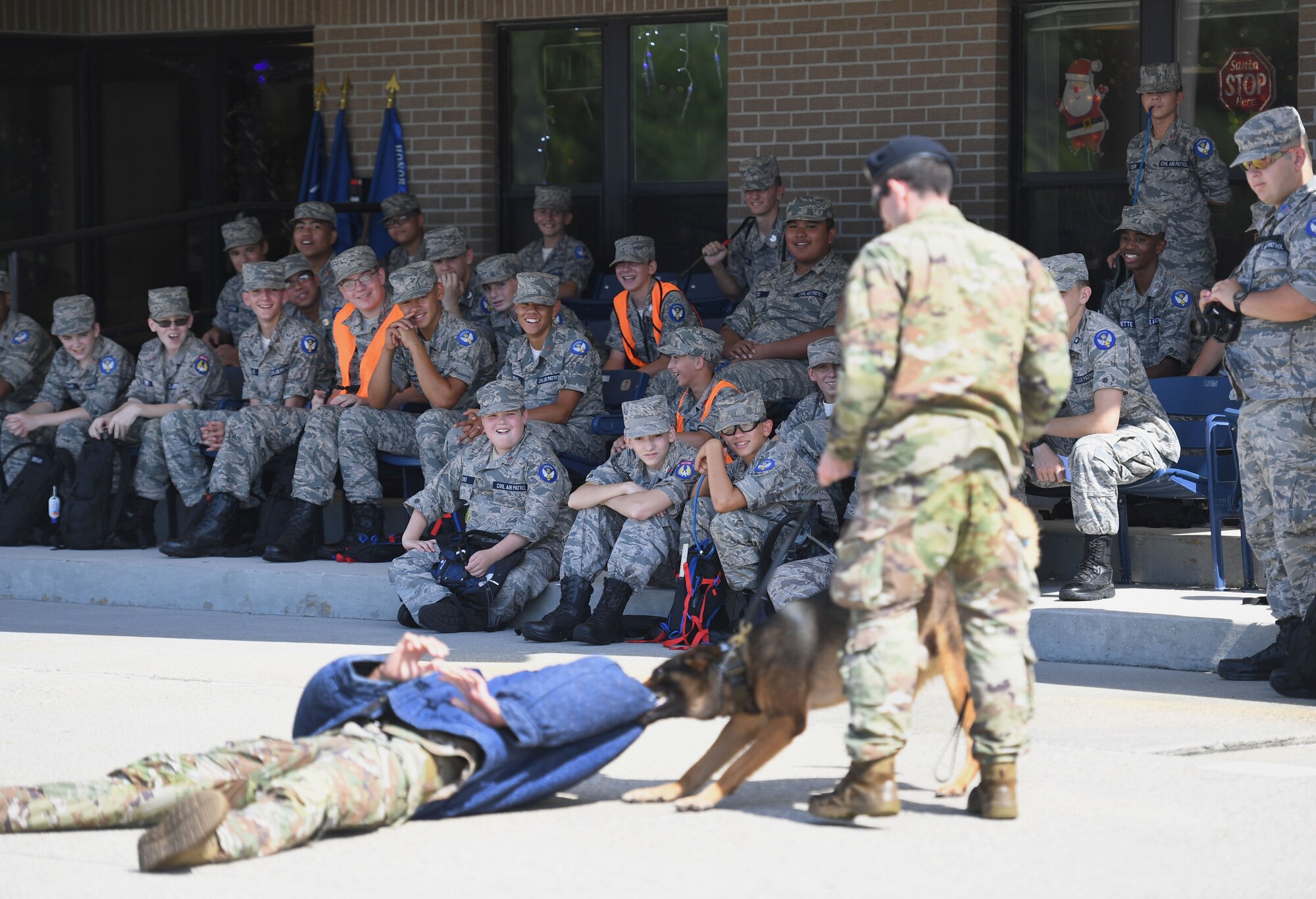 U.S. Air Force Staff Sgt. Dustin Hadsock and Senior Airman Anthony Seretis, 81st Security Forces Squadron military working dog handlers, and Rico, 81st SFS military working dog, perform a demonstration for Civil Air Patrol cadets on the Levitow Training Support Facility drill pad at Keesler Air Force Base, Mississippi, July 19, 2022. More than 50 cadets attended the Louisiana Wing Encampment at Keesler from July 14-24. (U.S. Air Force photo by Kemberly Groue)