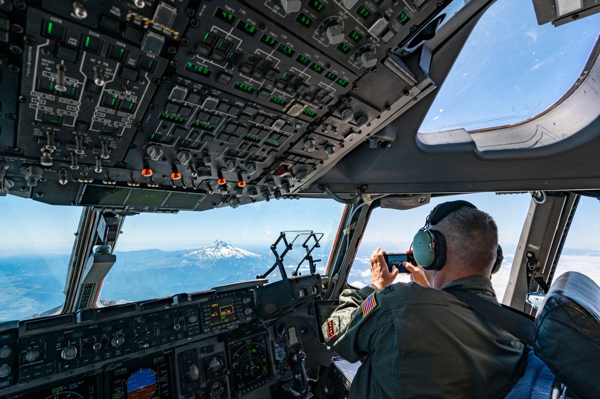 An Airman takes a photo from the flight deck of a plane.