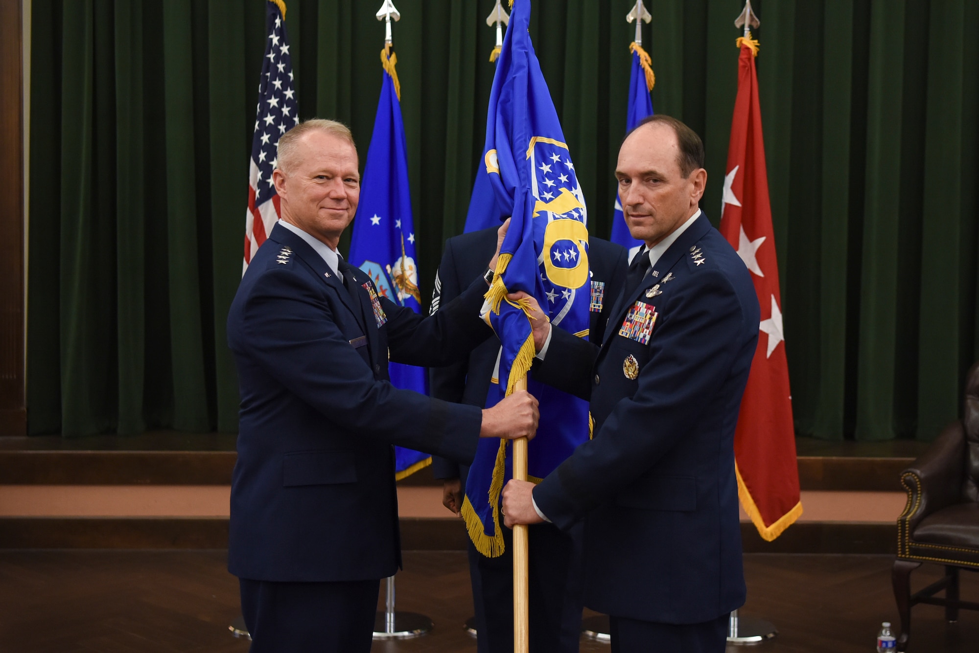 U.S. Air Force Gen. Mark Kelly, commander of Air Combat Command, passes the guidon to the new commander, Lt. Gen. Kevin Kennedy, during a change of command ceremony at Joint Base San Antonio-Lackland, Texas, July 21, 2022