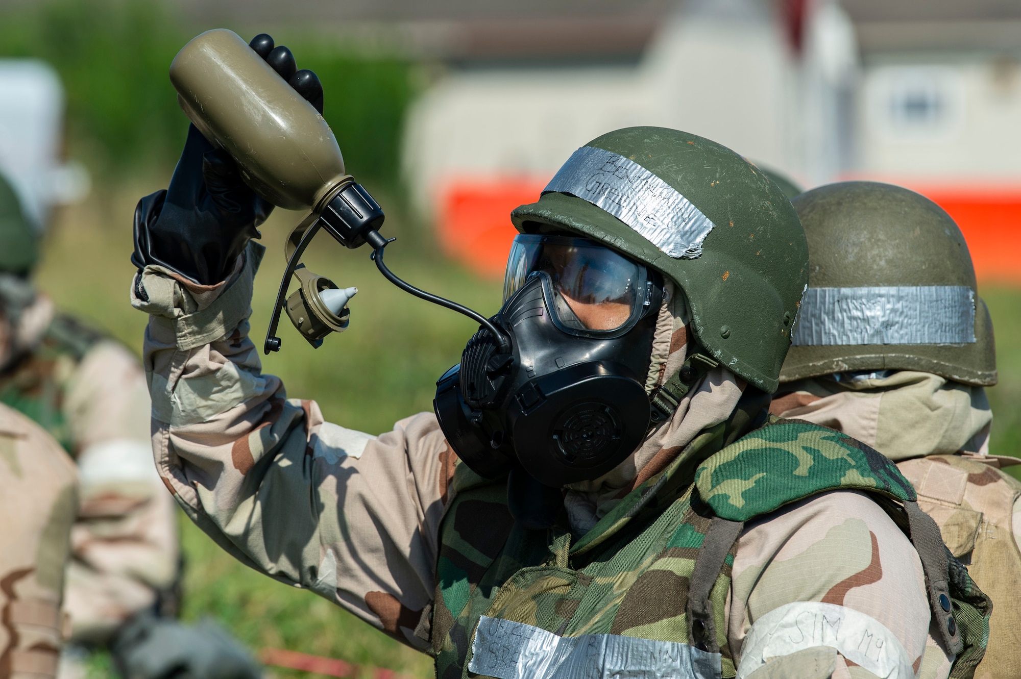 During a simulated attack, a Team Dover member wearing training protective gear hydrates while sitting in a simulated shelter during Liberty Eagle Readiness Exercise 2022 at Dover Air Force Base, Delaware, July 13, 2022. The 436th and 512th Airlift Wings tested their ability to generate, employ and sustain airpower across the world in a contested and degraded operational environment. (U.S. Air Force photo by Roland Balik)