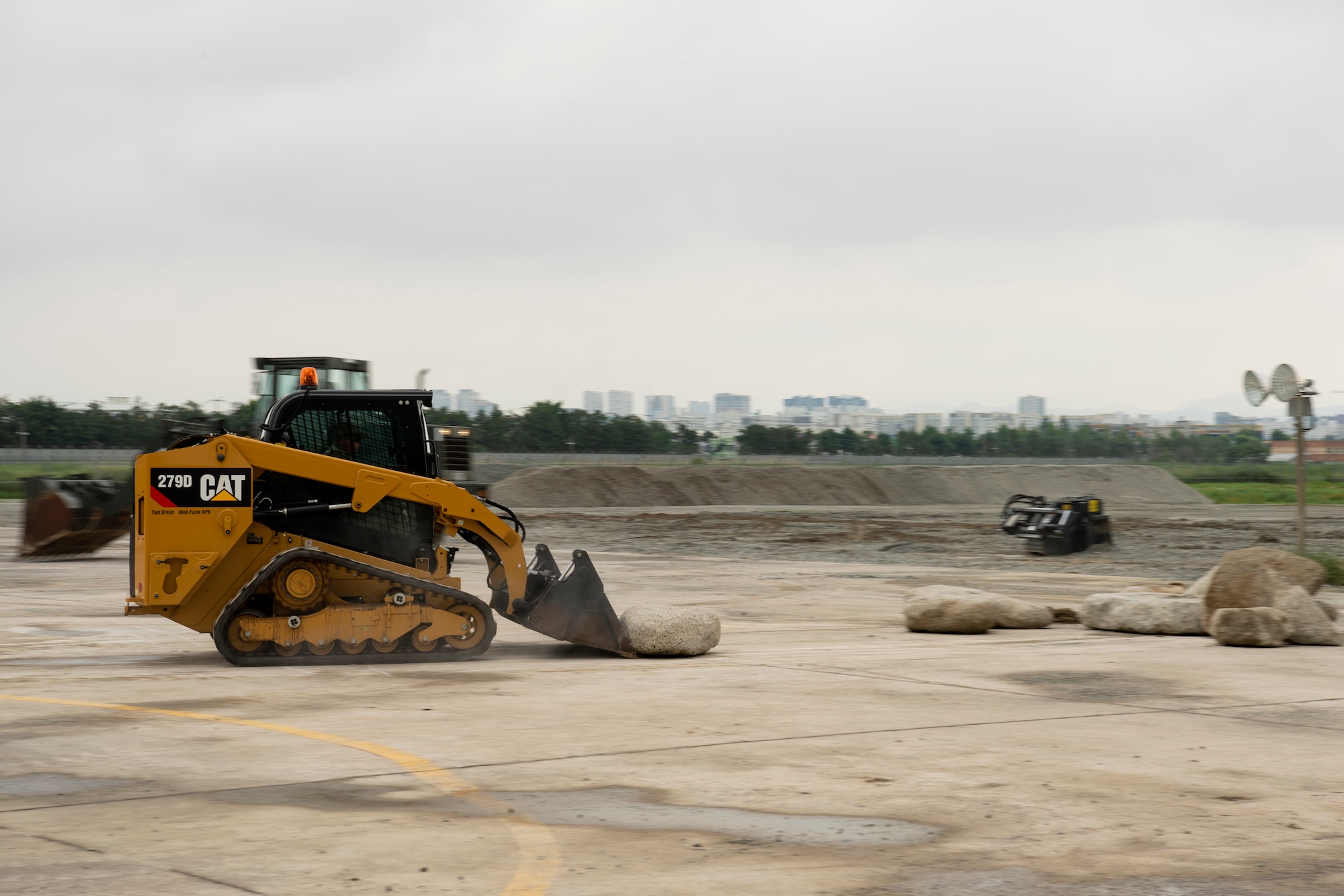 A U.S. Air Force (USAF) Civil Engineer Airman uses a Compact Track Loader with bucket attachment to clear debris during a rapid airfield damage repair training, July 19, 2022 at Gwangju Air Base, Republic of Korea.