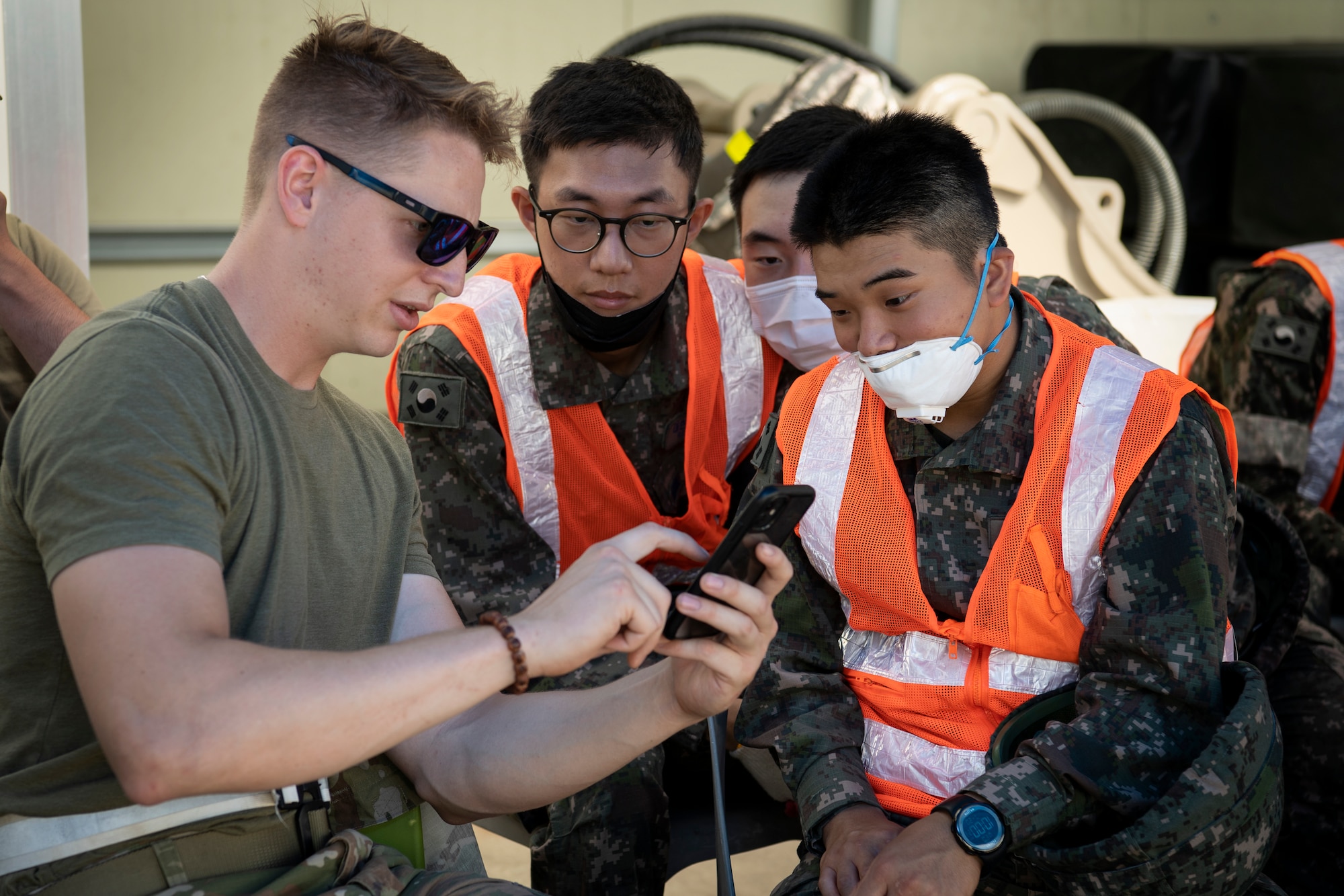 U.S. Air Force Airman 1st Class Preston Finch, a civil engineering structural apprentice, shows members of the Republic of Korea Air Force pictures of civil engineering projects that he completed in the past, during a rapid airfield damage repair training, July 19, 2022 at Gwangju Air Base, Republic of Korea.