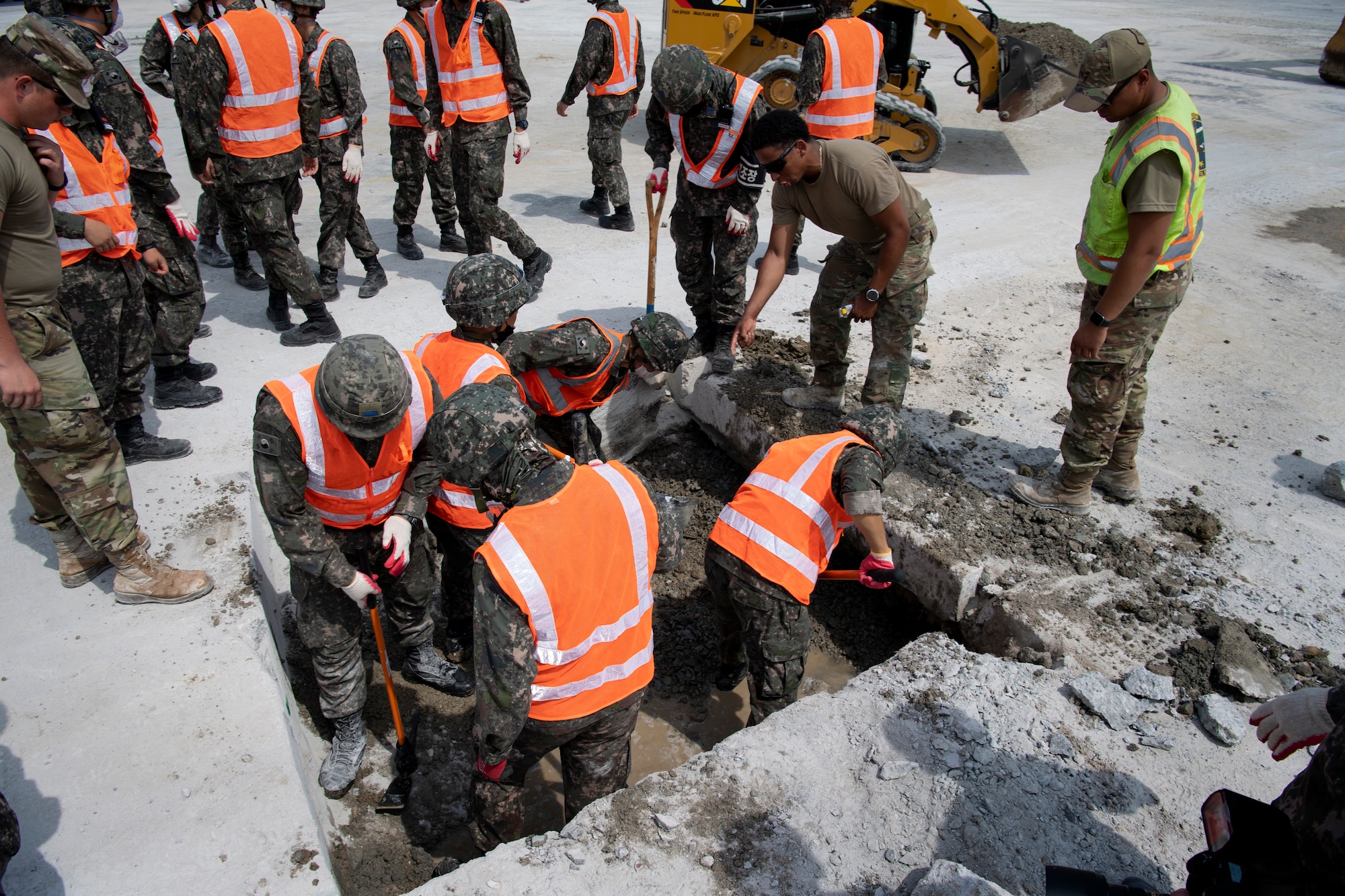 Civil engineers from the Republic of Korea and U.S. Air Force (USAF) clear debris from a hole in a cement training pad during a rapid airfield damage repair training, July 19, 2022 at Gwangju Air Base, Republic of Korea.