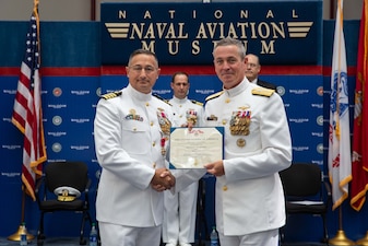 Rear Adm. Pete Garvin, commander, Naval Education and Training Command, right, presents the Legion of Merit to Capt. Marc W. Ratkus, commanding officer, Center for Information Warfare Training (CIWT), left, during the CIWT change of command ceremony at the National Naval Aviation Museum, July 22, 2022.  Capt. Christopher G. Bryant relieved Ratkus as CIWT’s commanding officer, while Ratkus also retired, concluding a 39-year military career. CIWT is charged with developing the future technical cadre of the Navy’s information warfare community.