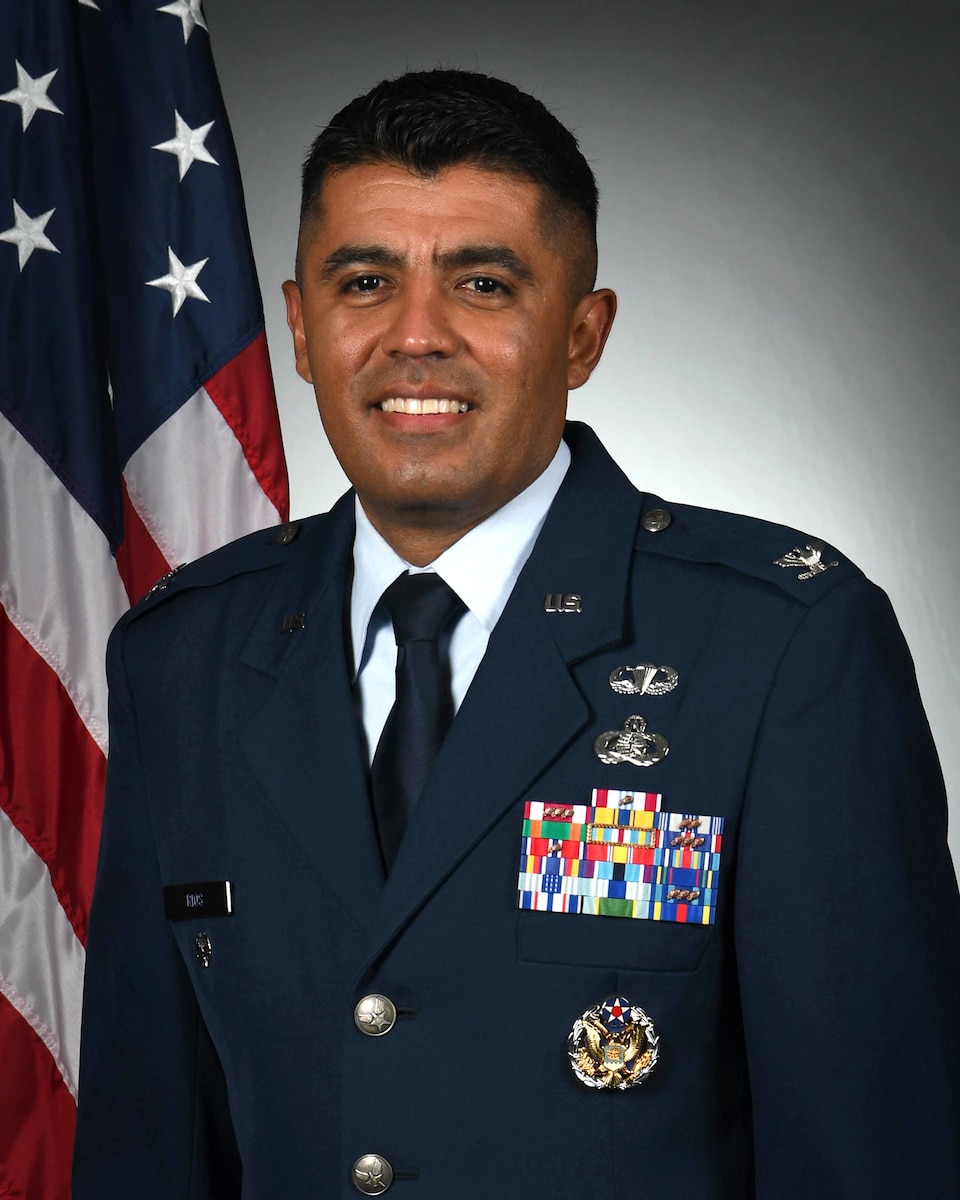 photo shows man in Air Force uniform in front of U.S. flag