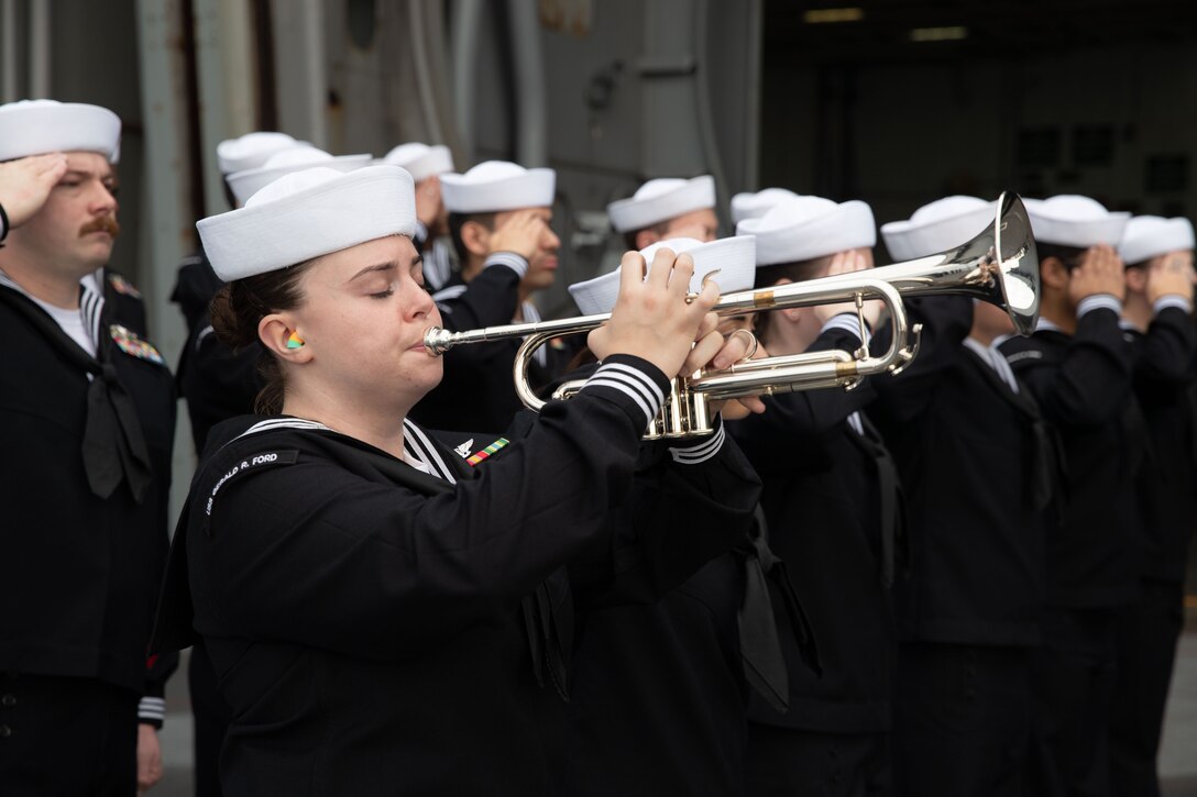 A sailor plays a trumpet.