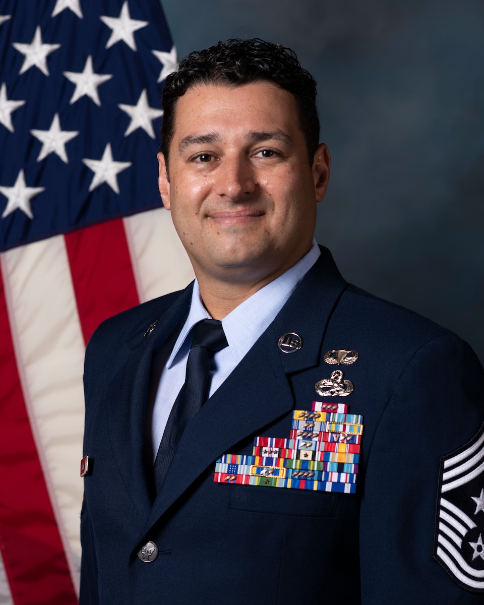 photo is man in Air Force uniform in front of U.S. flag