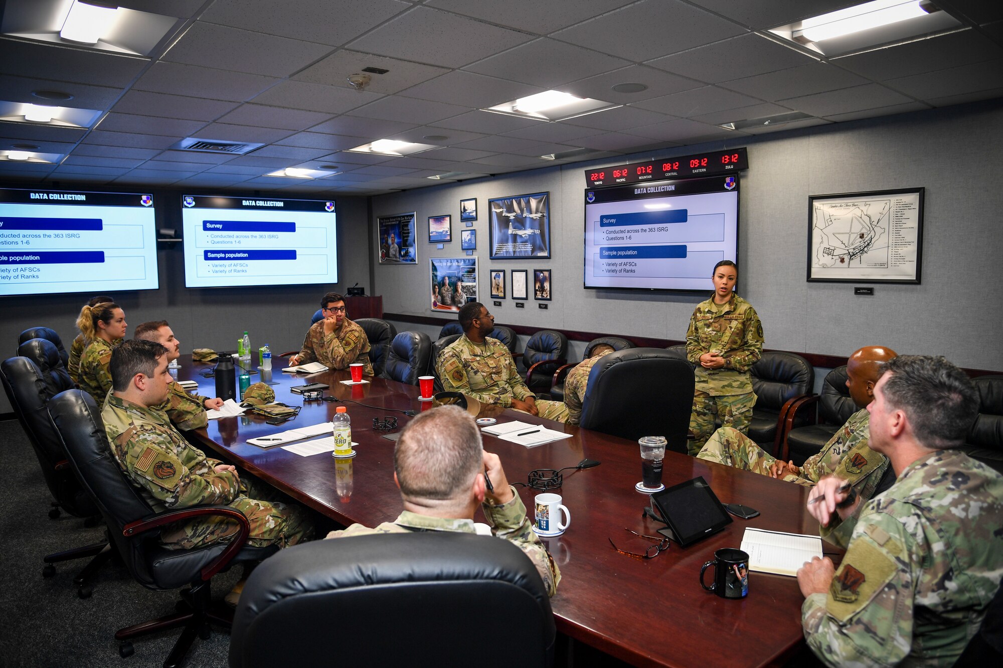 Airmen sit at a table and receive a brief.