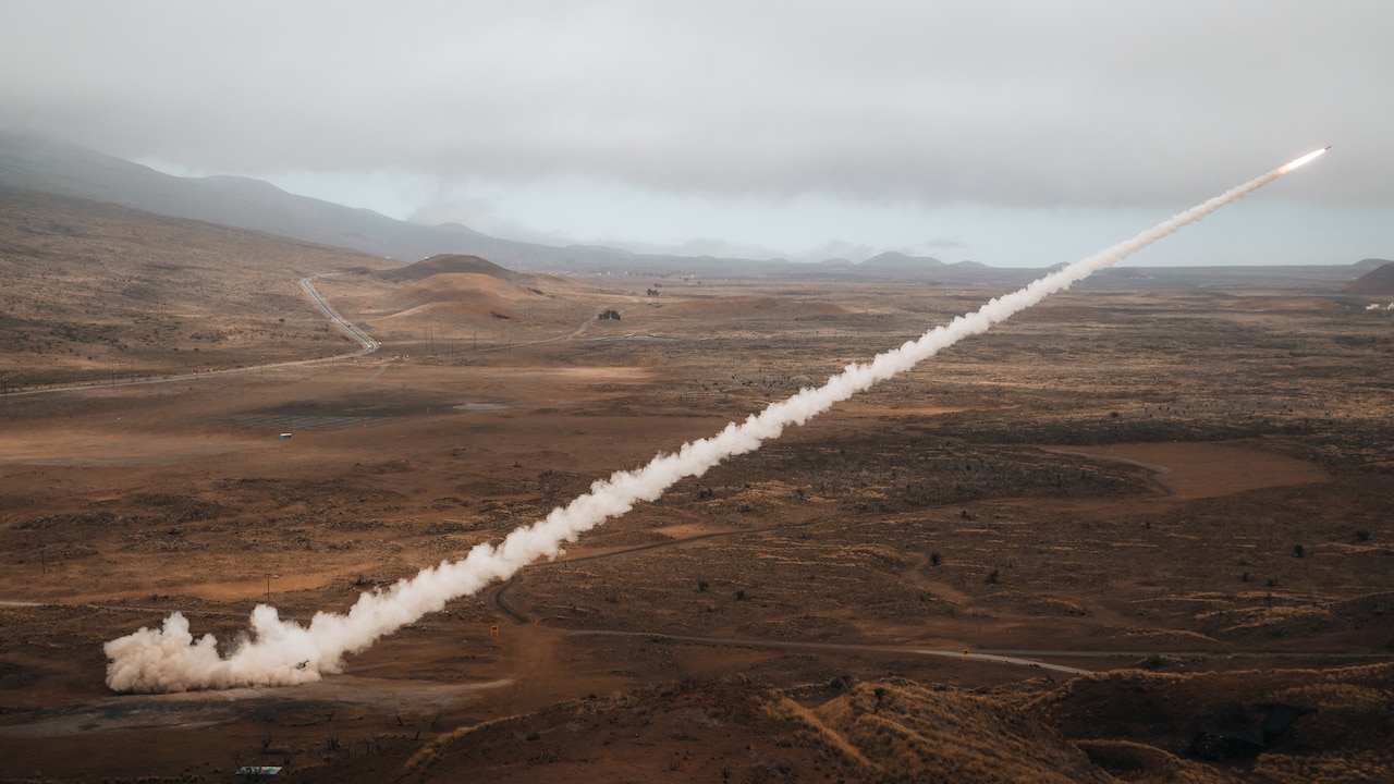A rocket leaves a smoke trail across the sky.
