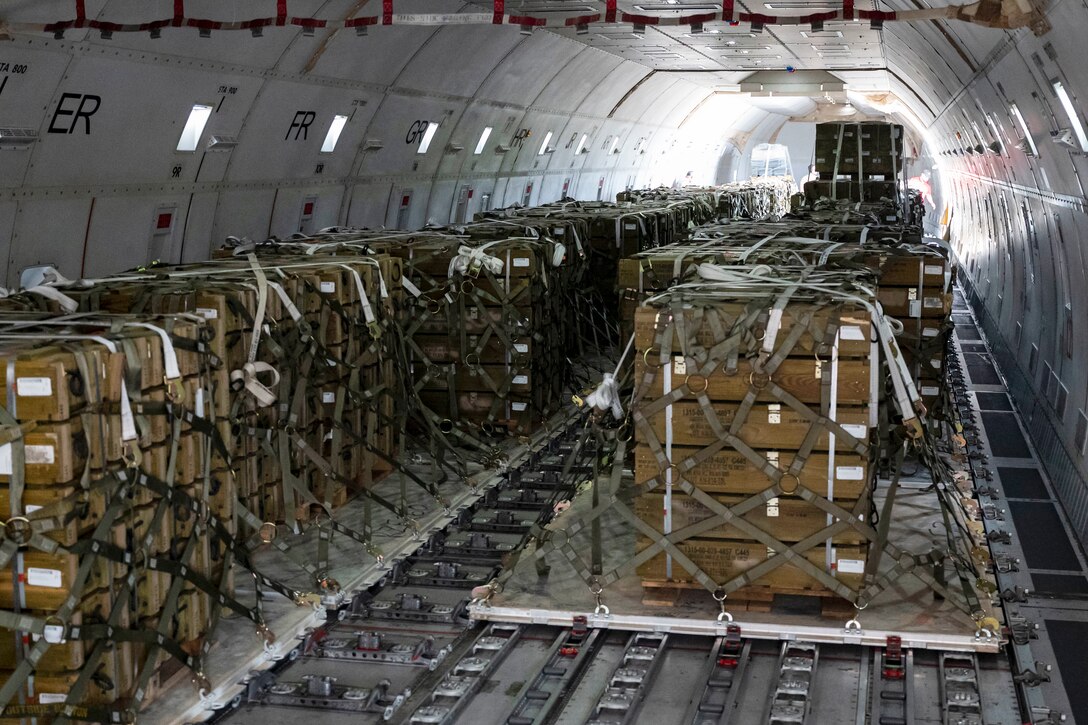 Pallets are tied down with webbing in an aircraft.