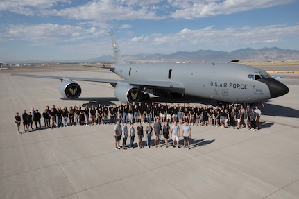 High school students stand in front of a KC-135 Stratotanker airplane for a group photo.
