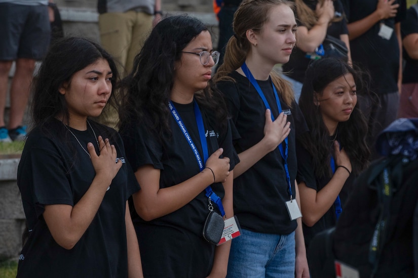 High school students stand with hands over heart.