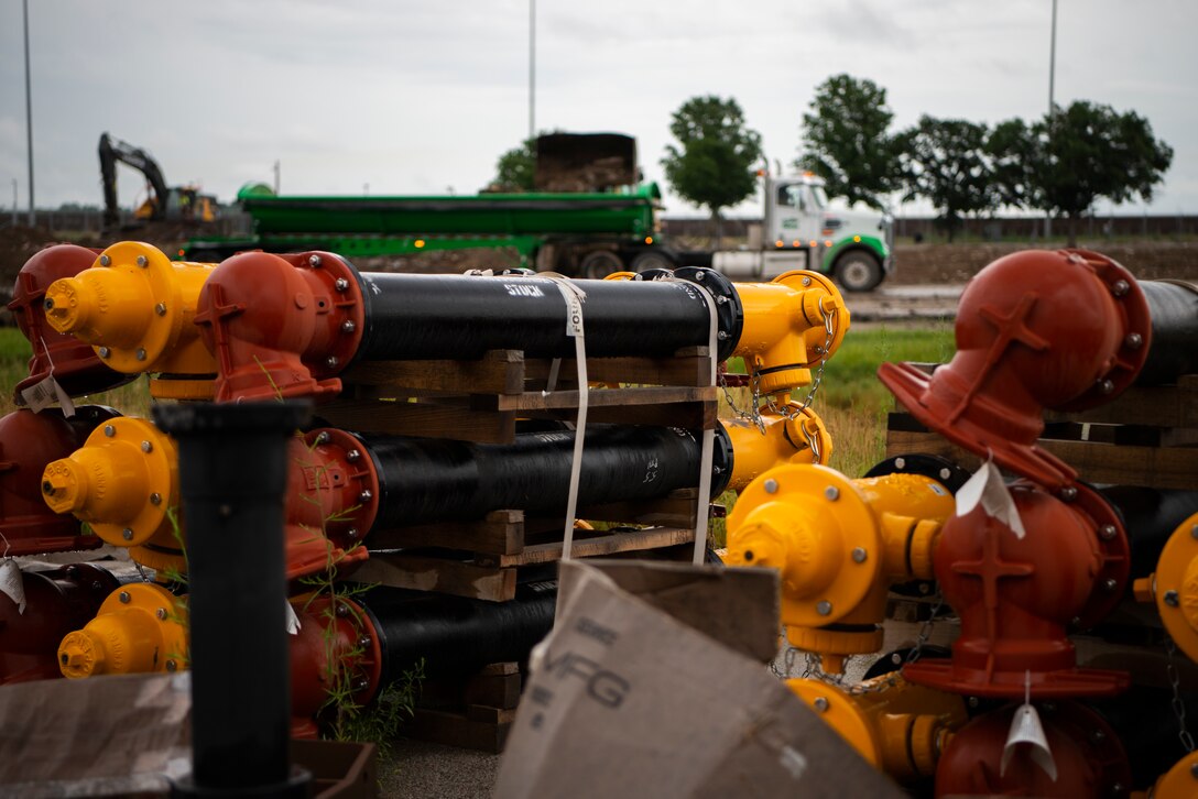 Parts are stored, ready to be installed into refurbished buildings as trucks remove dirt and debris on Offutt Air Force Base, Neb., July 7, 2022.