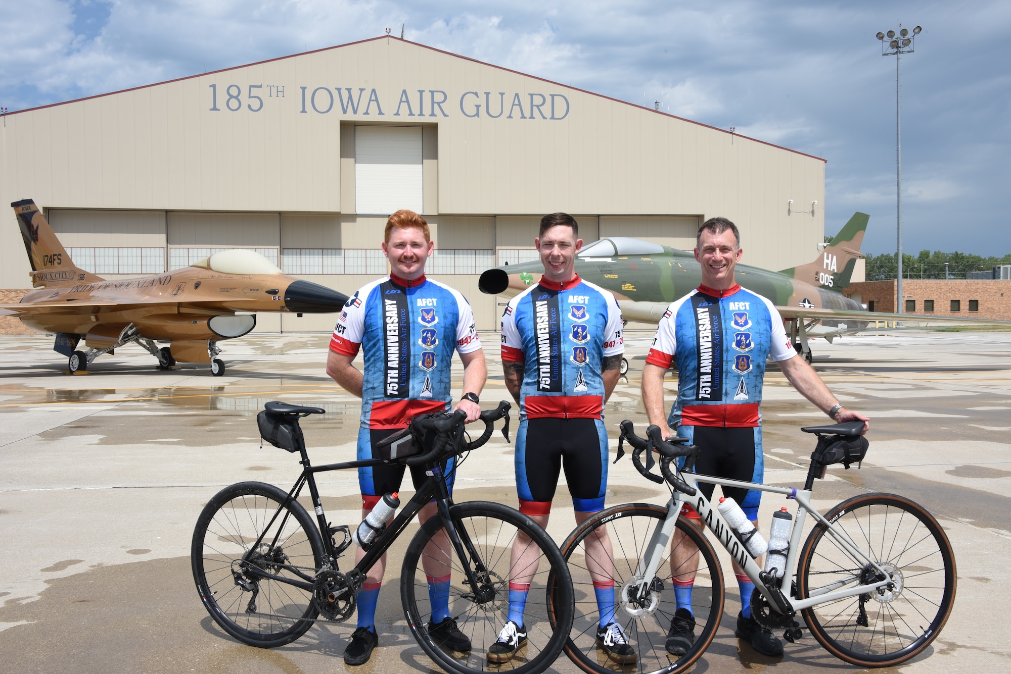 USAFE Airmen of the Air Force Cycling Team pose in front of an F-16 Fighting Falcon