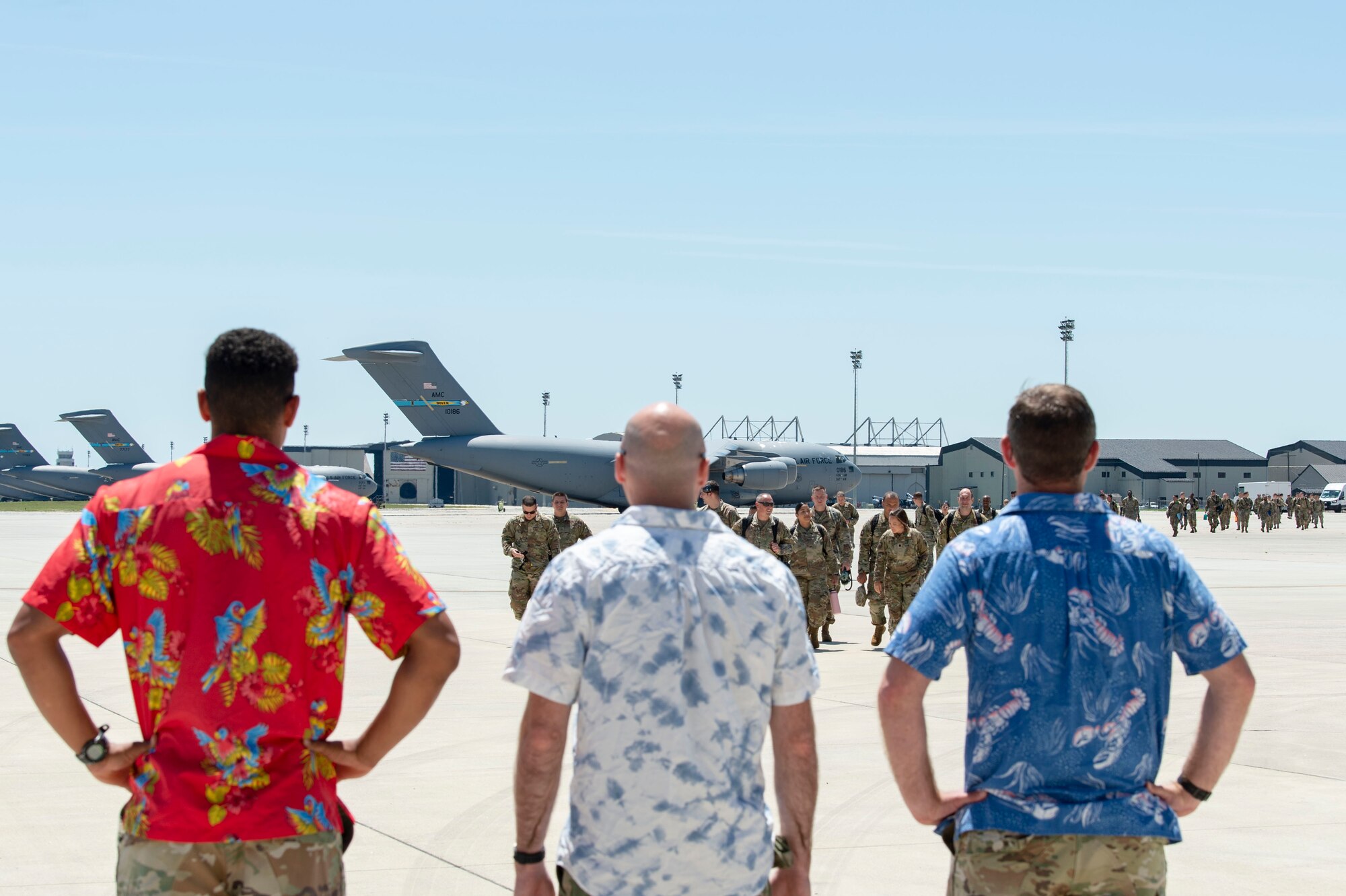 After disembarking a C-17 Globemaster III, Team Dover members walk up to three individuals acting as host-nation greeters at a simulated deployment location during Liberty Eagle Readiness Exercise 2022 at Dover Air Force Base, Delaware, July 11, 2022. The 436th and 512th Airlift Wings tested their ability to generate, employ and sustain airpower across the world in a simulated contested and degraded operational environment. (U.S. Air Force photo by Roland Balik)