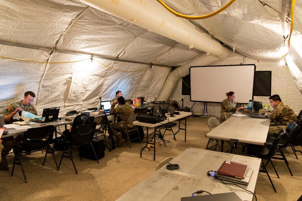 Team Dover members work inside a tent located at a simulated forward operating base during Liberty Eagle Readiness Exercise 2022 at Dover Air Force Base, Delaware, July 12, 2022. The 436th and 512th Airlift Wings tested their ability to generate, employ and sustain airpower across the world in a simulated contested and degraded operational environment. (U.S. Air Force photo by Roland Balik)
