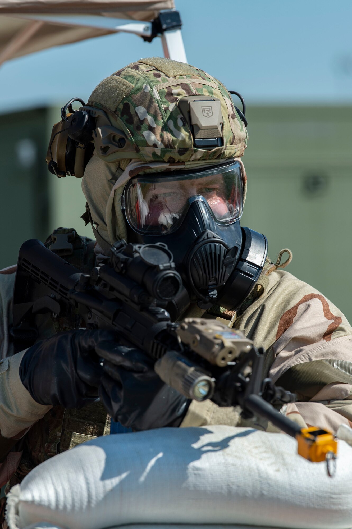 A Team Dover member wearing training protective gear stands guard against possible intruders at a simulated forward operating base during Liberty Eagle Readiness Exercise 2022 at Dover Air Force Base, Delaware, July 13, 2022. The 436th and 512th Airlift Wings tested their ability to generate, employ and sustain airpower across the world in a contested and degraded operational environment. (U.S. Air Force photo by Roland Balik)