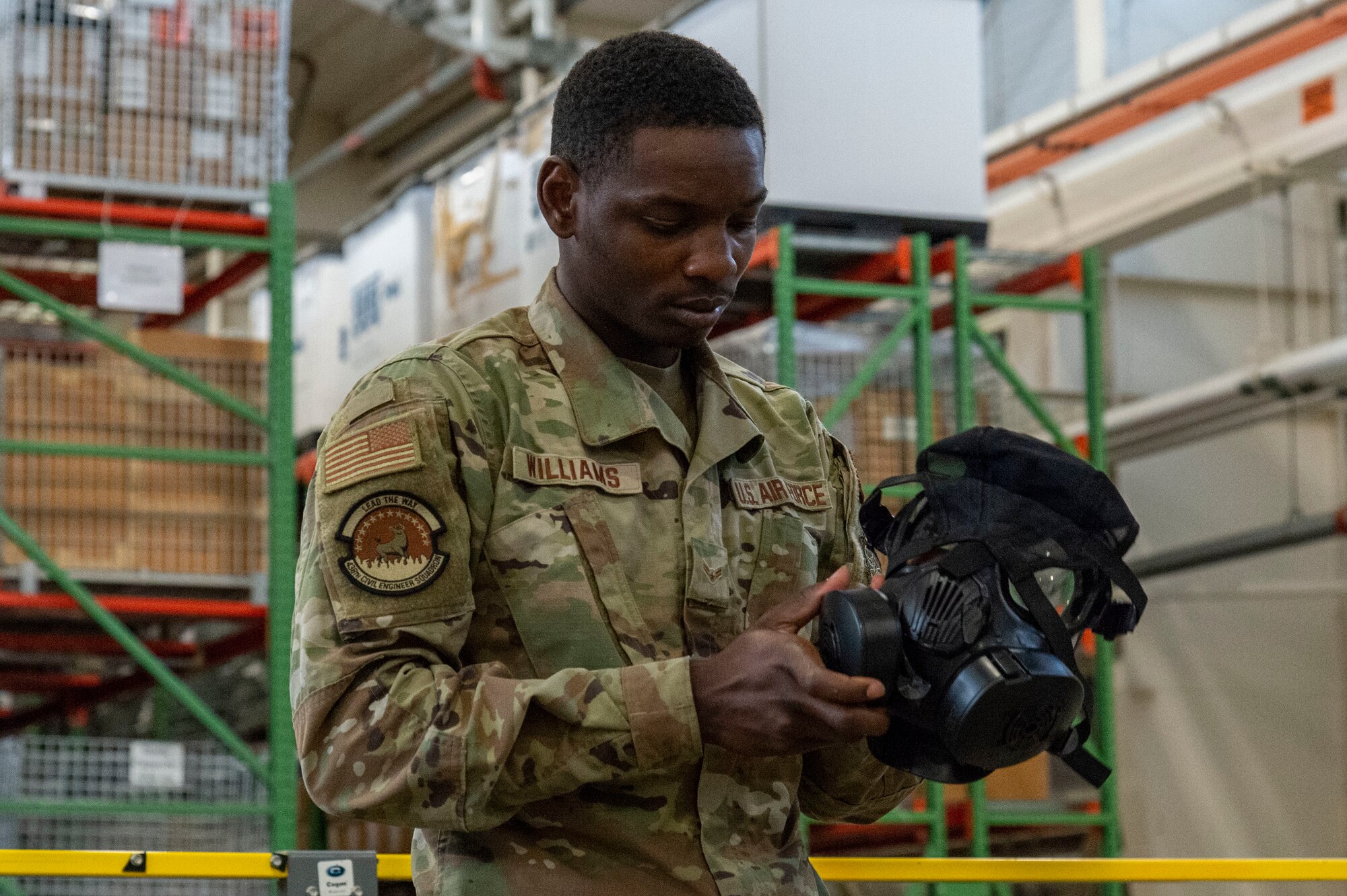 Airman 1st Class Davien Williams, 436th Civil Engineer Squadron pavement and equipment apprentice, inspects his mask as he processes through the personnel deployment function line during Liberty Eagle Readiness Exercise 2022 at Dover Air Force Base, Delaware, July 11, 2022. The 436th and 512th Airlift Wings tested their ability to generate, employ and sustain airpower across the world in a simulated contested and degraded operational environment. (U.S. Air Force photo by Roland Balik)