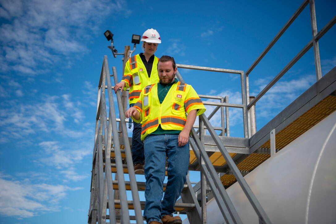 Zachary Smedley, Fuels Mechanical Engineer, U.S. Army Corps of Engineers, Omaha District, leads Portia Lenczowski, fuels section student trainee, down the steps after reviewing the work performed on the newly installed fuel tanks at Offutt Air Force Base, Neb.