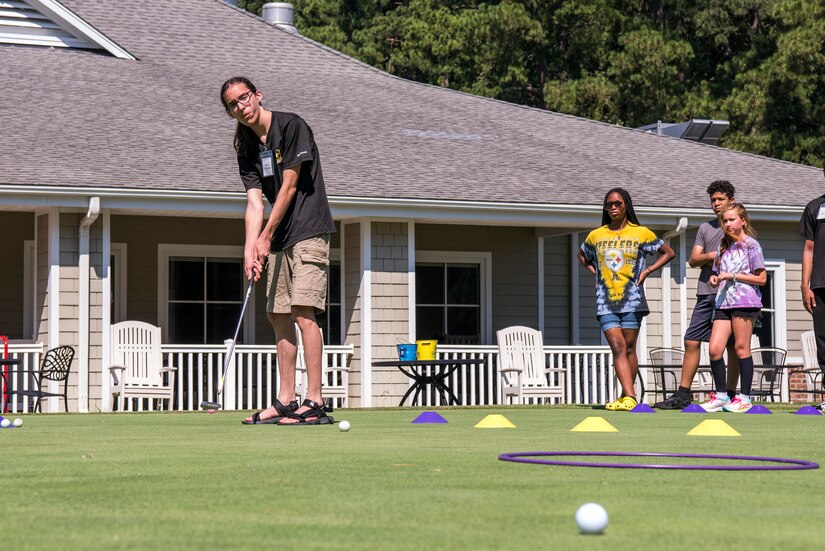 High school students hits a golf ball during summer camp.