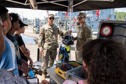Soldiers teach high school students above dive equipment.